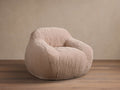 Front view of the light pink Snugg Faux Fur Kids Chair, a cozy, generously padded chair on a wooden floor.