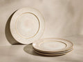 Front view of speckled ivory Solenne Dinner Plates (Set of 4), one upright, three stacked, showcasing their glossy finish.