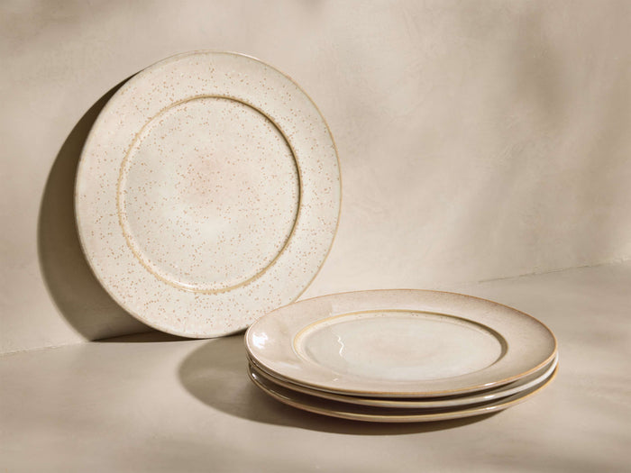 Front view of speckled ivory Solenne Dinner Plates (Set of 4), one upright, three stacked, showcasing their glossy finish.