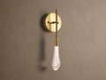 Soltaire Sconce: Round brass backplate, vertical arm, and glowing teardrop glass shade with internal bubbles mounted on a wall.