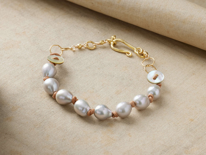 Thalassa Bracelet: White freshwater pearls, tan hemp cord, gold vermeil details, mother-of-pearl button accents, hook clasp on linen.
