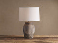Thornton Table Lamp with distressed dark grey terracotta base, light linen drum shade, on a rustic wooden table.