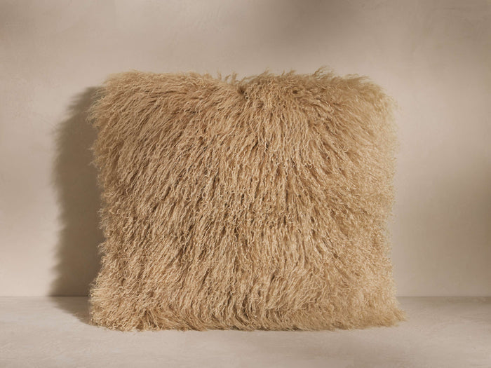 Square Tibetan Longwool Pillow in light sandy brown, covered in long, curly sheepskin, standing on a light background.