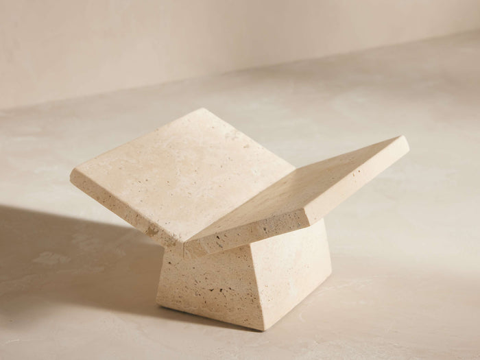 Light beige travertine book stand with two angled slabs forming an open book shape, resting on a solid base. Natural stone texture.