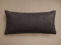 Charcoal grey Treccia Woven Lumbar Pillow, horizontal, featuring an intricate basket-weave leather texture on a tan wall.
