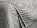 Close-up of a soft grey Tulaya Cotton Quilt with vertical quilting stitches and a detailed frayed edge.
