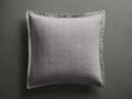 Tulaya Cotton Sham, light gray square sham with quilted pattern and frayed edges, resting on a dark gray surface.