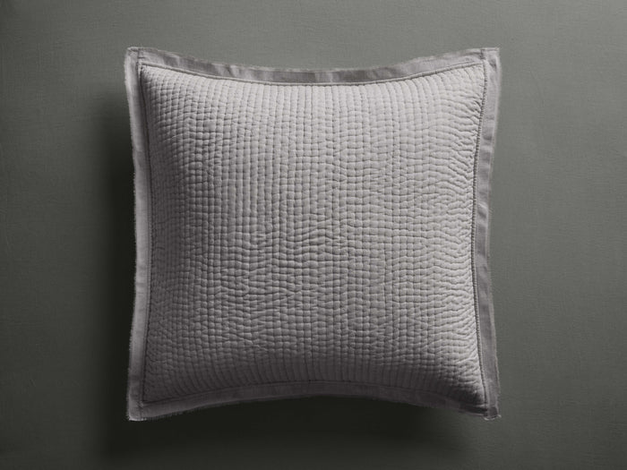 Tulaya Cotton Sham, light gray square sham with quilted pattern and frayed edges, resting on a dark gray surface.