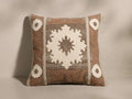 Front view of a square terracotta cushion with a large white geometric star and smaller corner motifs, bordered by taupe stripes.