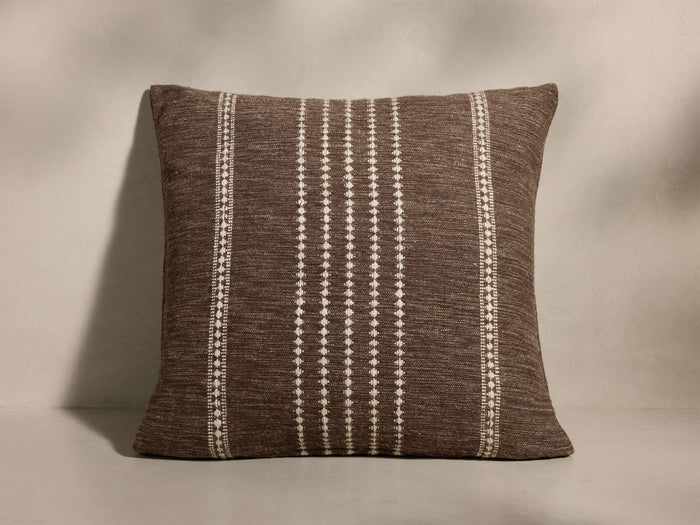Front view of a brown throw pillow with white dotted vertical stripes down the center and patterned borders.