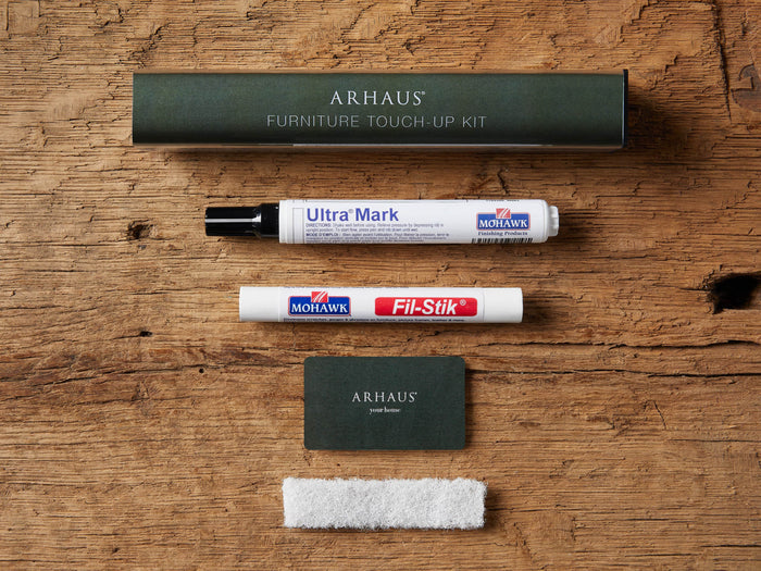 Arhaus Tuscany Finish Touch Up Kit: dark green box, Ultra Mark pen, Fil-Stik, Arhaus card, and white pad on wood.