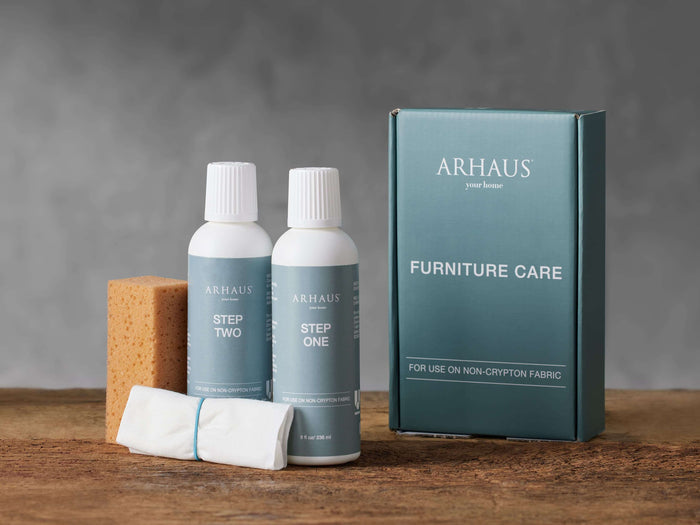 Front view of Upholstery Cleaning Kit, with two white 'Step One' & 'Step Two' bottles, brown sponge, white cloth, and teal Arhaus box.