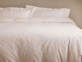 Soft, off-white Washed Percale Duvet, gently wrinkled, on a bed with two matching pillow shams, against a plain wall.