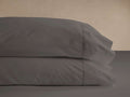 Two dark gray Washed Sateen Pillowcases stacked neatly, showcasing their subtle sheen and decorative stitching.