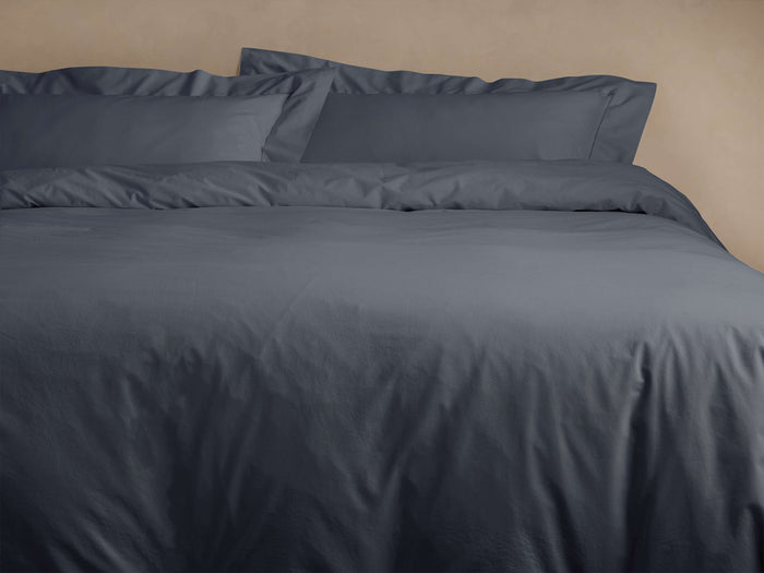 Washed Sateen Sheet Set in dark blue-gray, showing a duvet cover and two pillows on a bed, looking soft and luxurious.