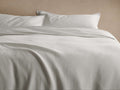 Off-white Washed Waffle Duvet Set on bed, with two shams. Soft folds highlight its subtle, textured waffle weave pattern.