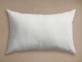 White rectangular Water Repellent Outdoor Core Insert pillow, plump and horizontal on a light brown background.