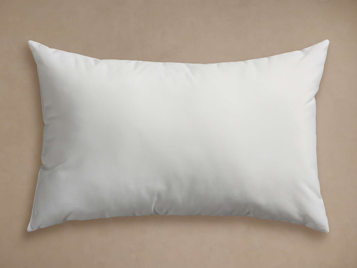 White rectangular Water Repellent Outdoor Core Insert pillow, plump and horizontal on a light brown background.