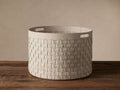 Light-colored Wilona Nubuck Basket, woven, cylindrical with reinforced handles, sits on a wooden floor against a plain wall.