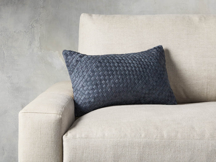 Woven Hide Lumbar Pillow Cover, gray basket-weave leather, on a light beige sofa, showcasing its texture and design.