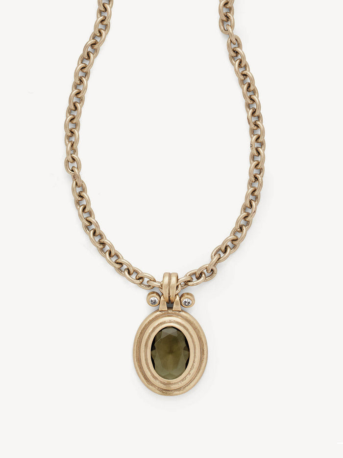 A gold-toned chain necklace with a textured oval pendant featuring a dark olive-green stone, set against a plain off-white background.