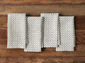 Zadie Napkins set of 4 displayed on a wooden surface. Each napkin has a geometric block-printed pattern in blue on white linen fabric.